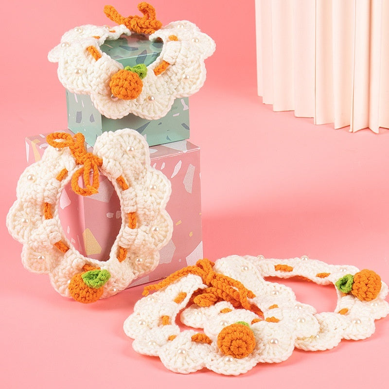 Écharpe tricotée pour chat avec motifs floraux et orange, parfaite pour accessoiriser votre animal avec style.