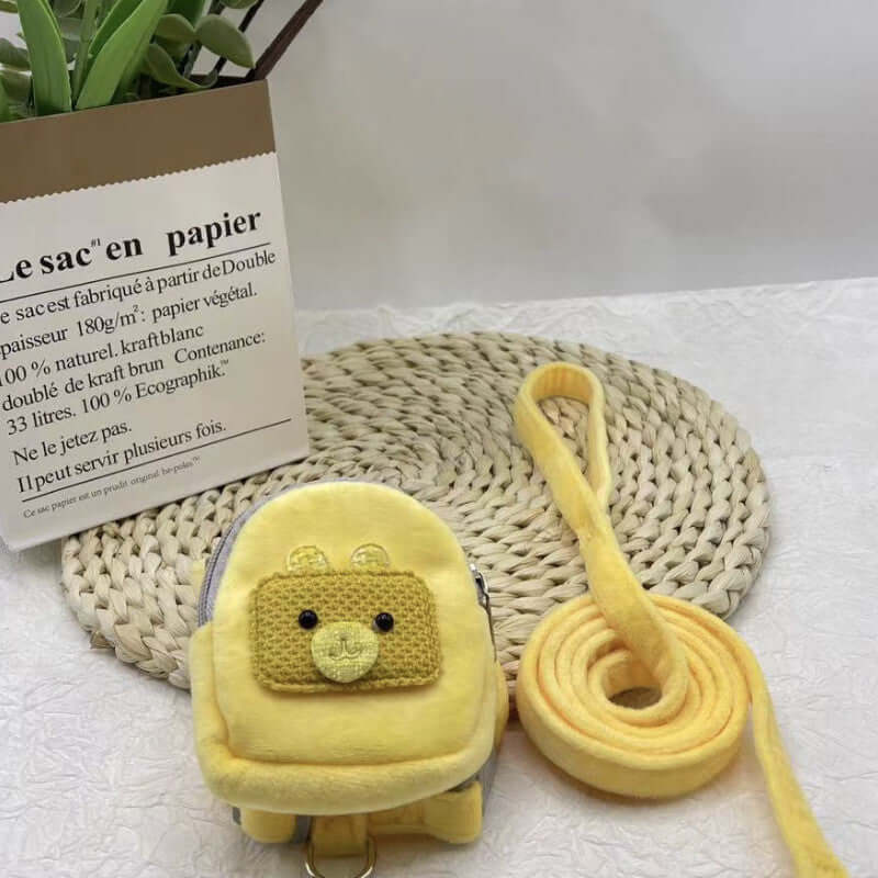Sac à dos jaune pour animaux avec harnais et corde de traction sur une serviette blanche.
