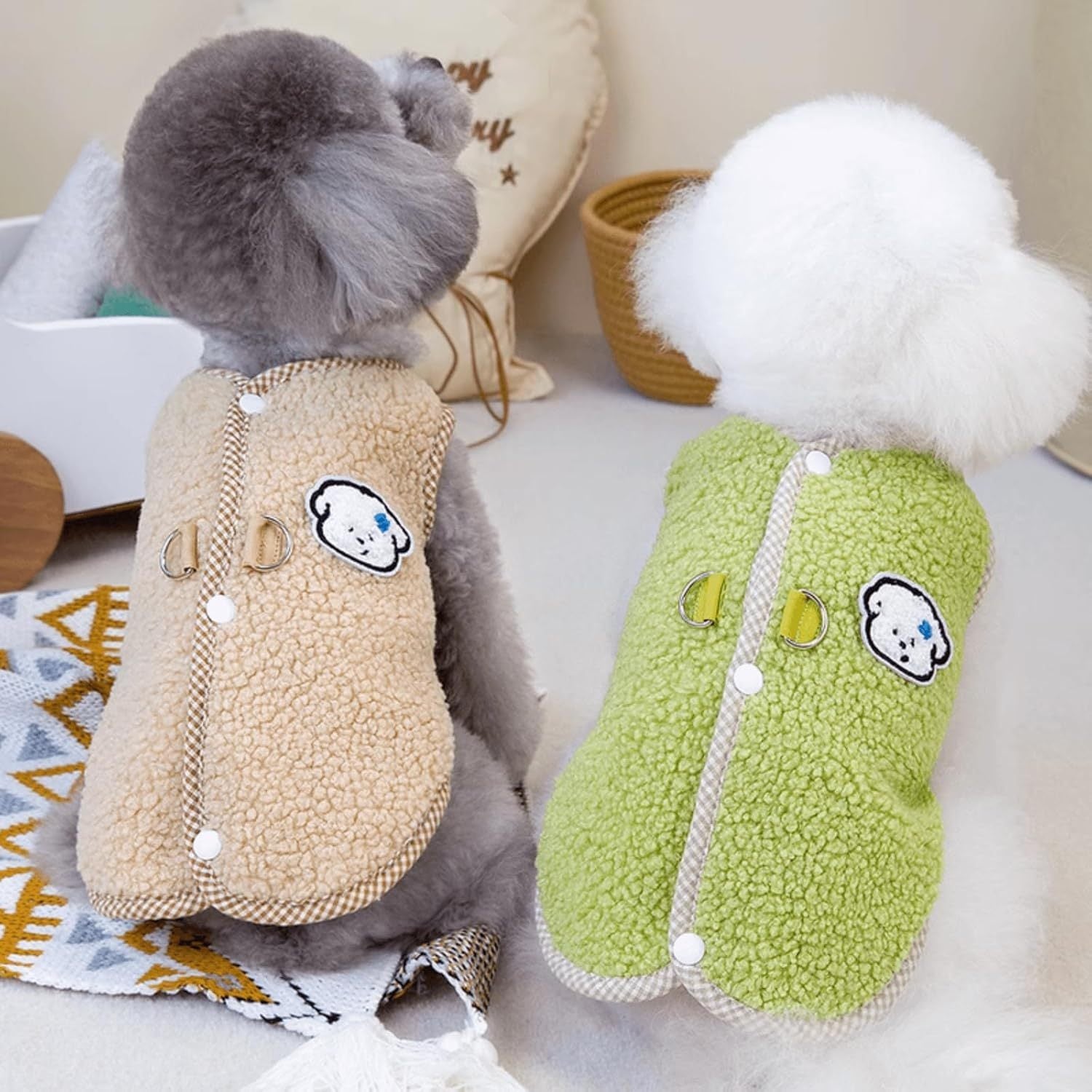 Deux chiens portant des gilets en polaire, l'un beige et l'autre vert, avec des motifs mignons, parfaits pour l'automne.