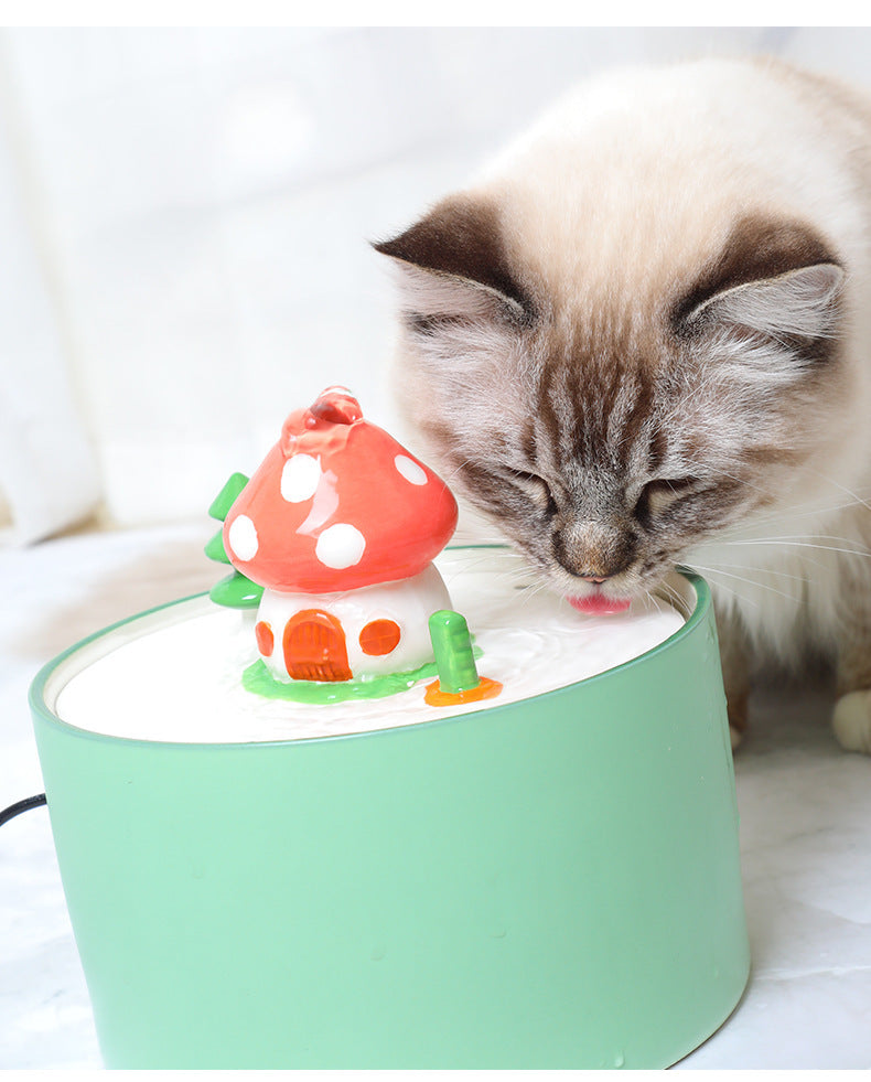 Chat buvant de l'eau d'une fontaine électrique en céramique en forme de champignon.