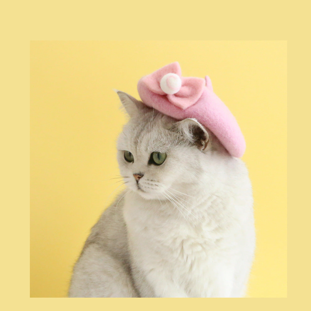 Chat portant un chapeau en laine rose modèle Cherry sur fond jaune, ajoutant charme et confort.