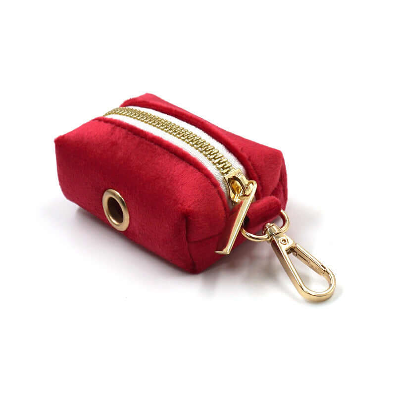 Pet accessory: red velvet bag with zipper and gold hardware for storing dog waste bags.