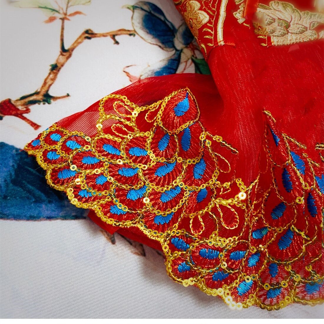 Détails en broderie dorée sur le bord d'une robe chinoise rouge éclatante, fond floral.