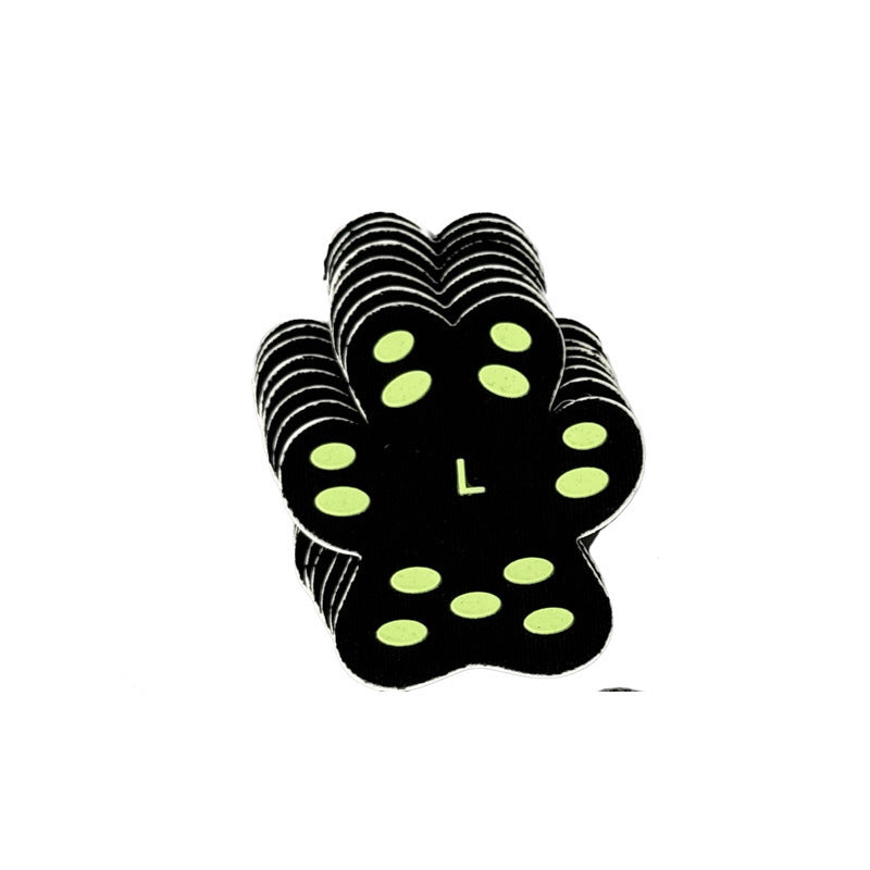 Patch de protection pour pattes de chien en forme de patte, en silicone noir avec marquage vert.