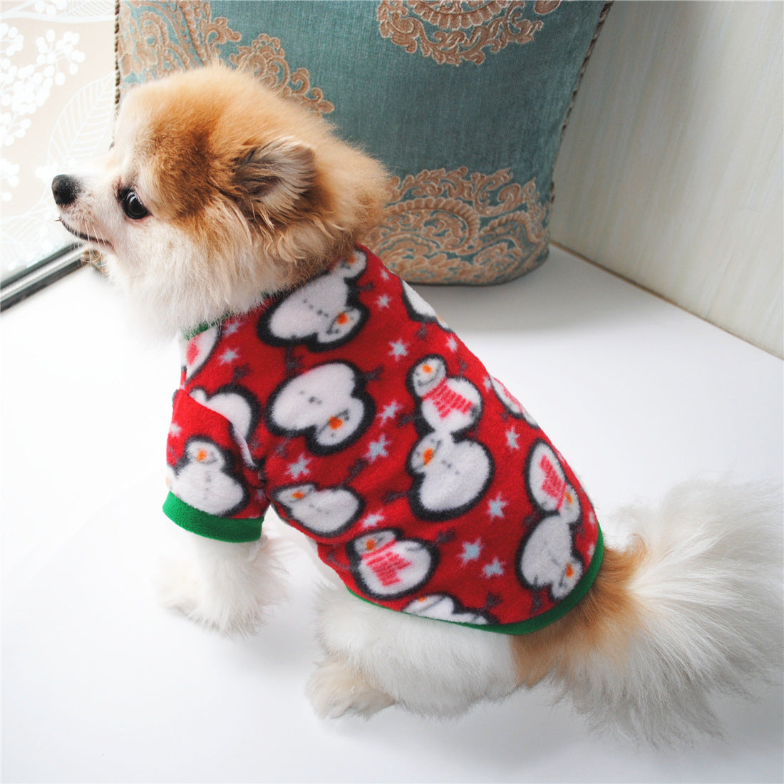 Chien Pomeranien portant un pull de Noël en polaire avec motif bonhomme de neige, parfait pour l'hiver