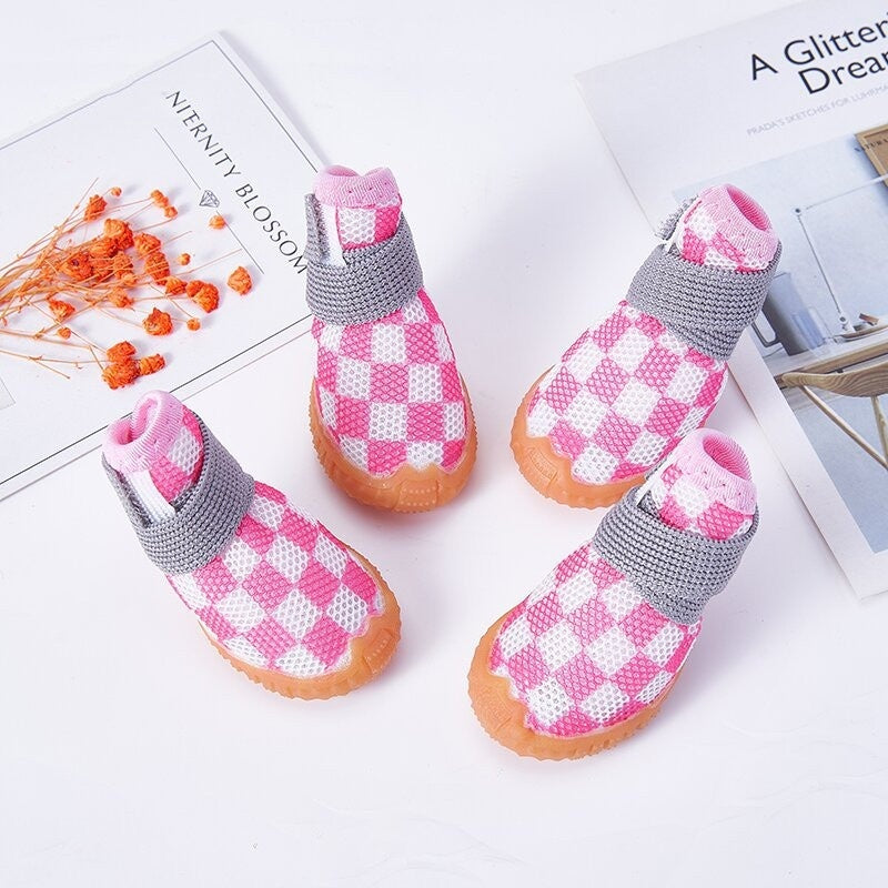 Chaussures pour chiens non-dérapantes en motif à carreaux roses et grises sur un fond blanc.
