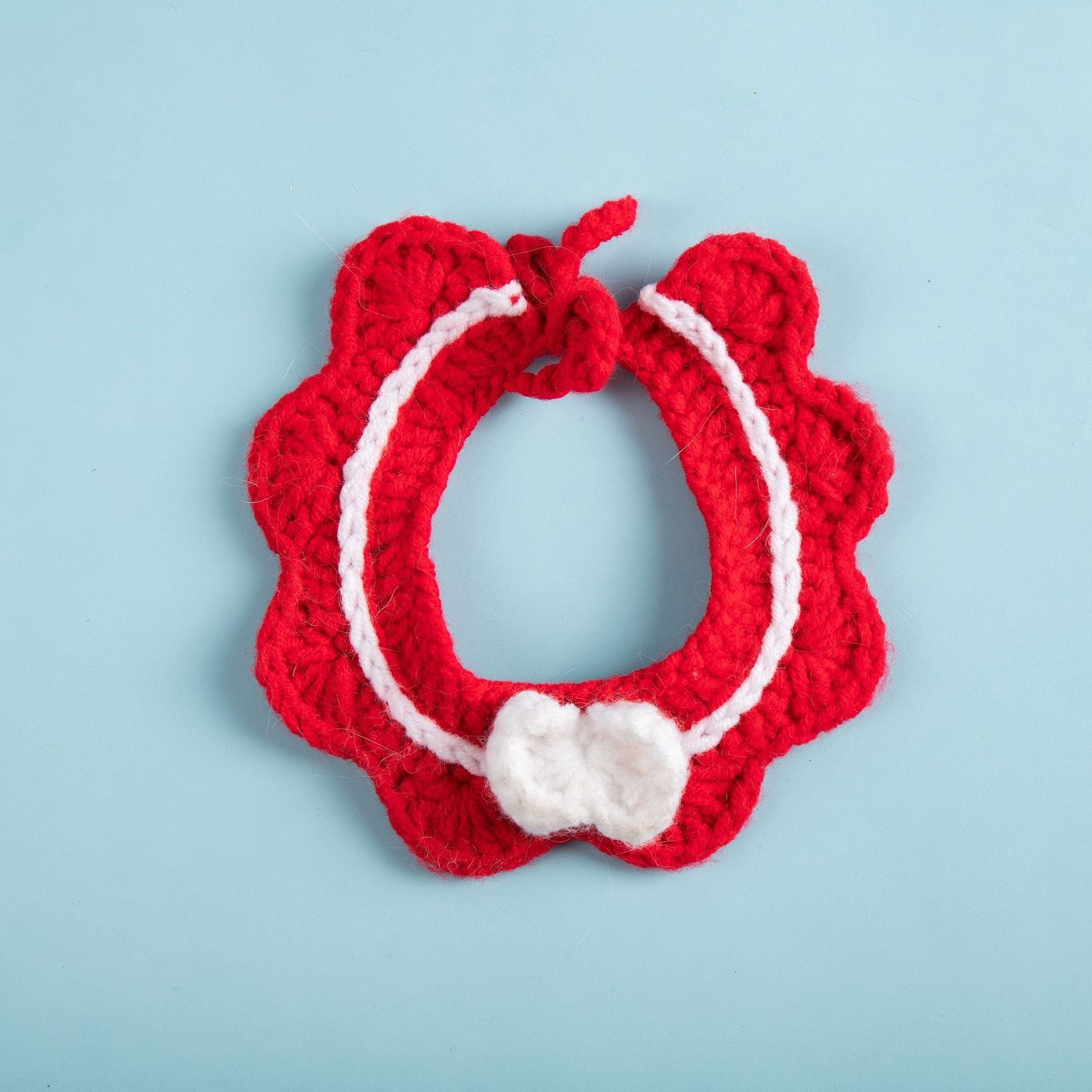 Écharpe tricotée rouge pour chat avec nœud blanc, accessoire stylé pour animaux, confortable et mignon.