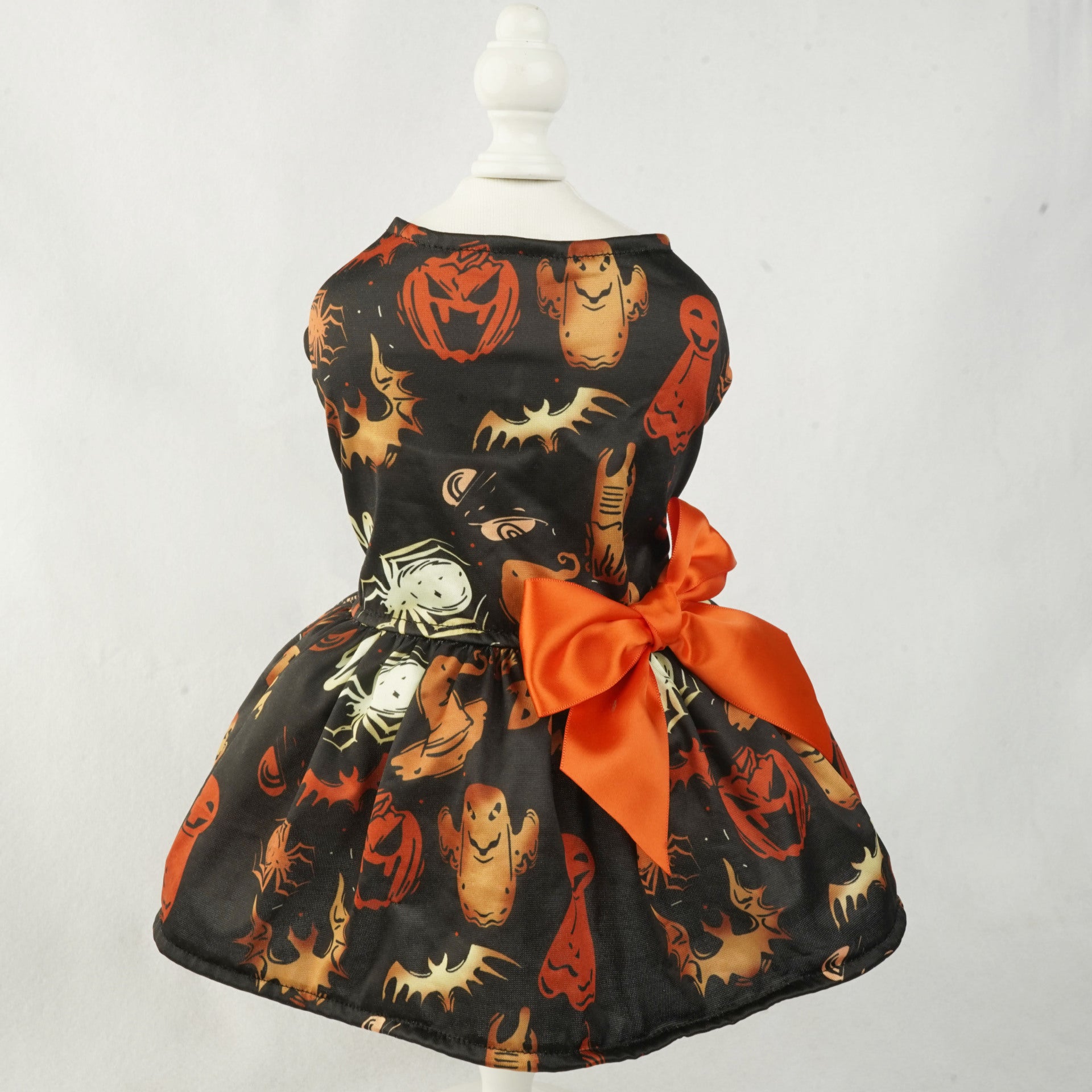 Robe d'Halloween pour petit chien imprimée de citrouilles et fantômes avec un nœud orange.
